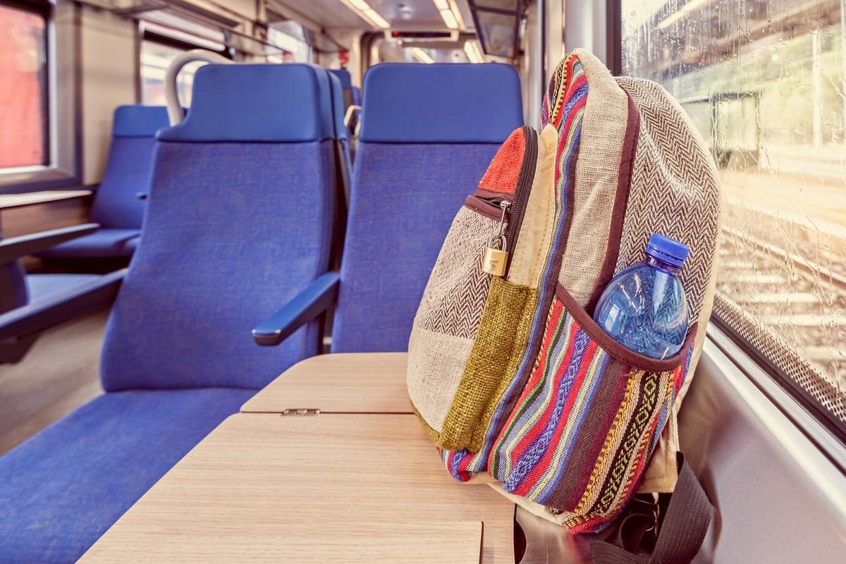 Mały plecak z przekąskami, kolorowanką i zabawkowym autobusem na stoliku w pociągu